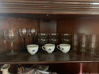 Glass goblet, wine glasses, champagne coupes, tumblers, teacups visible on shelf
