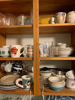 Cupboard shelves showing mixed mugs, plates, bowls, glasses