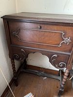 Full view of closed cabinet showing dark brown wood, carved details, barley-twist legs