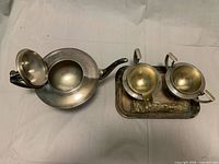 Top view of teapot opened, creamer, sugar bowl lid removed, tray showing gilt interiors and overall form