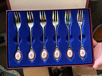 Six silver-plated dessert forks with porcelain floral medallions in blue-lined presentation box