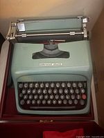 Top view of seafoam green Underwood Olivetti manual typewriter in open red-lined case