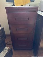 Front view of brown 4-drawer wood veneer filing cabinet showing drawers and handles