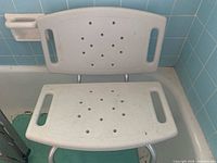Overall shot of white plastic shower seat with backrest in bathtub