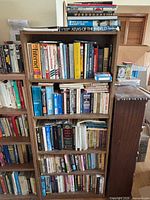 Front view of wood bookshelf filled with diverse books and small tins
