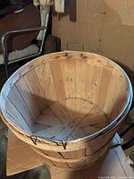 Overall view of staved wooden bushel basket with metal bands and wire handle
