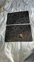 Two black cat litter catcher mats lying flat showing overall size and pattern