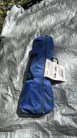 Blue zipped carry bag containing Coleman Screw Shelter placed on tarp