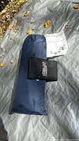 Blue tent carry bag, instruction manual, black accessory pouch on top of grey ground sheet