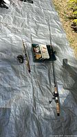 Full view of two rods with reels and tackle box on tarp