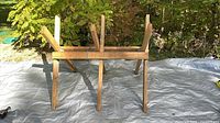 Full view of wooden folding log saw stand upright on tarp
