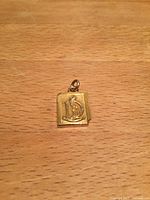 Front view of gold book pendant showing embossed 15 motif and bail