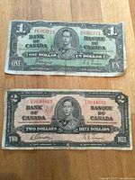 Fronts of 1937 $1 and $2 Bank of Canada notes showing King George VI and serial numbers