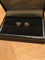 pair of gold flower stud earrings with diamonds in jewelry box, front view