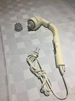 Massager with attached single-point head, loose multi-node head, cord visible