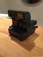 Front three-quarter view of Polaroid OneStep CloseUp 600 camera with flash housing raised