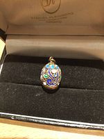 Pendant in presentation box, top view showing enamel colors and patterns