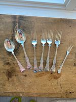 Group shot of all seven flatware pieces laid out on wood surface
