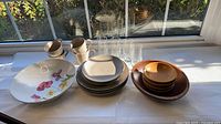 All items laid out: plates, mugs, tumblers, floral bowl, wooden bowls