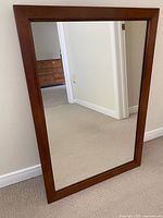 Front view of rectangular wood framed mirror leaning against wall