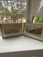 Both framed watercolor paintings displayed side by side on windowsill