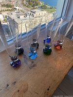 Six flared beer glasses with coloured sculpted bases on table