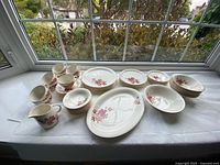 Full set displayed on windowsill showing plates, bowls, cups, saucers, platter, vegetable bowls and creamer
