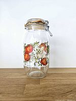 Full view of clear glass canister with printed produce motif, lid closed