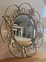 Frontal view of brass convex mirror with scroll and leaf frame