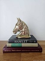 Single brass horse head bookend displayed on stacked books