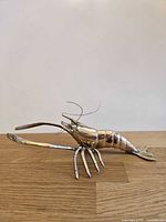 Side view of brass lobster figurine showing body, legs, and claws