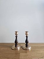 Front view of both candlestick holders showing brass bases and wooden stems
