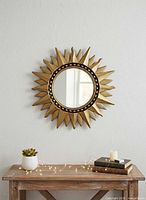 Front view of gold sunburst convex mirror hanging on wall