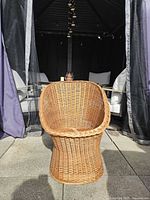 Front view of woven rattan bucket chair showing hourglass base and seat shape