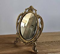 Front angled view of brass vanity mirror showing frame detail and stand