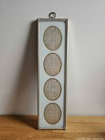 Front view of brass frame showing four oval openings and ornate border