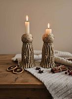 Pair of tassel candlestick holders displayed with lit taper candles for scale