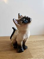 Front three-quarter view of glazed ceramic Siamese cat figurine