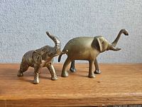 Two brass elephant figurines on wood shelf