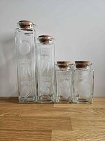 Front view showing four etched vegetable canisters with corks inserted