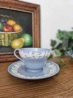 Cup on saucer showing white grapevine relief detail