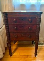 Front view of chest showing three drawers, spool-turned legs, wooden knobs, keyholes