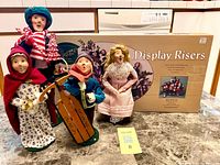 Group shot of four caroler figurines and boxed display risers
