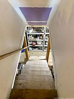 View down basement stairs showing shelving packed with dinnerware
