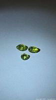 Three loose peridot gemstones on neutral background