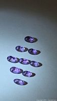 Nine oval purple amethyst stones arranged on surface