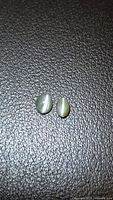Two alexandrite cabochons on textured surface showing cat’s eye