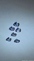 Six trillion-cut tanzanites arranged on neutral background