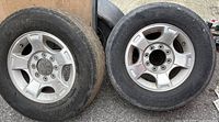 Front view of two Ford F-250 aluminum rims with worn tires