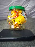 Overall lot showing Bear Peanut Butter glass jar with green lid filled with small Winnie the Pooh plush toys